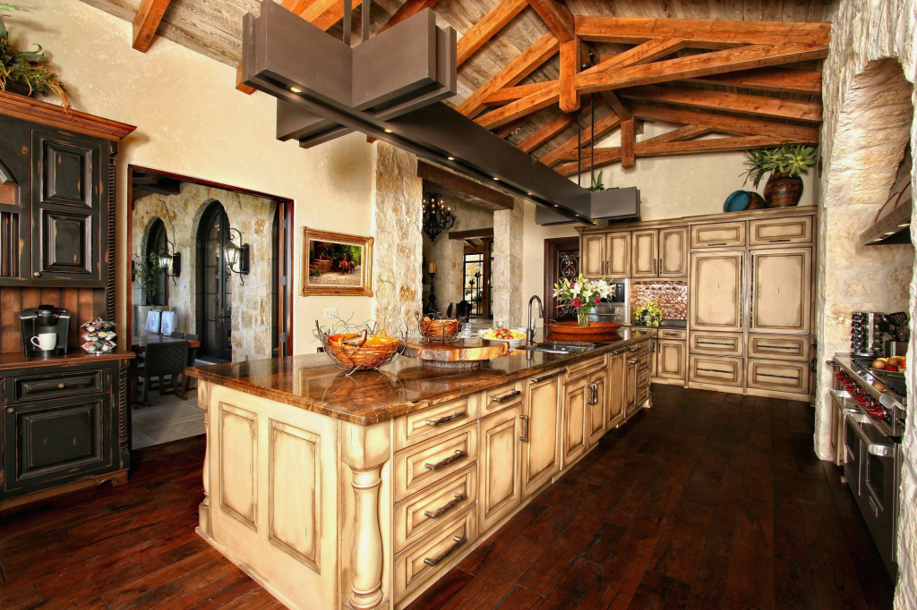 If you're going for more of an English farmhouse type of design, this can commonly be done if you remove the existing drywall and ran more decorative stained wood beams on the ceiling. This kitchen design idea is for the luxurious dream kitchen. It provides more than enough storage to organize to your hearts content with an extended island countertop with lighting and dark stained wood against light countertops.