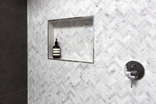 Shower shelf detail in wall of herringbone marble tiles in a luxury new home